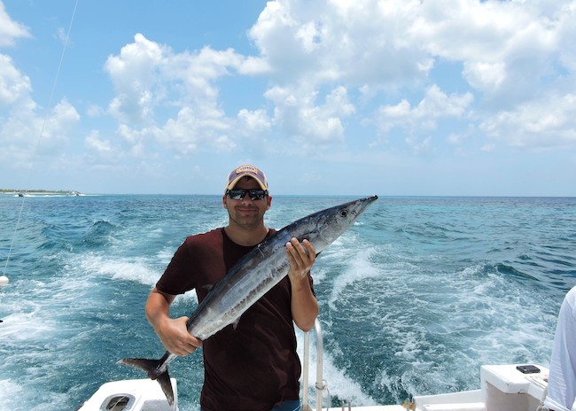 Sam is happy to catch a big fish on his first fishing tour in Cozumel.