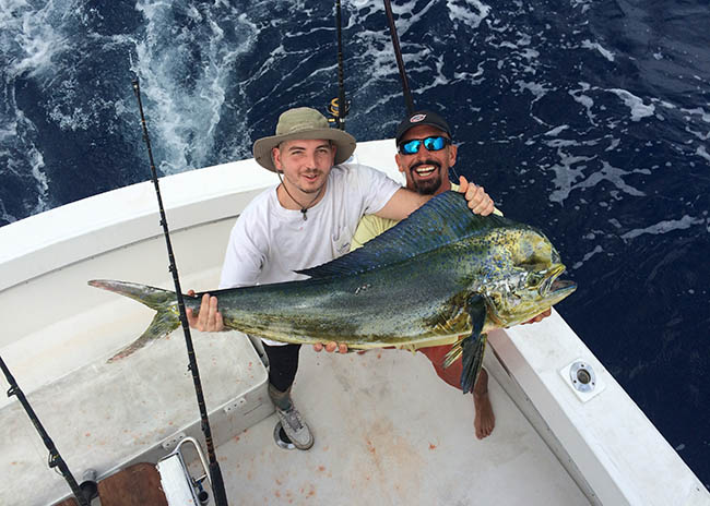 Stephen and his brother laughing with happiness while holding their catch.